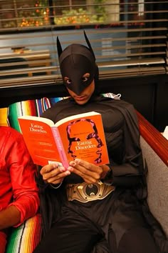 two people dressed as batman and reading books