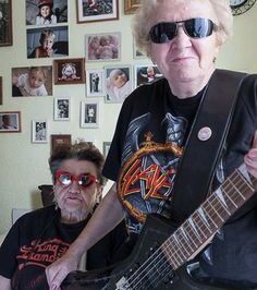 an older woman with sunglasses on holding a guitar in front of a man sitting down