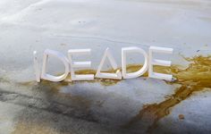 the word deade spelled out in white letters on top of some dirty cement and water