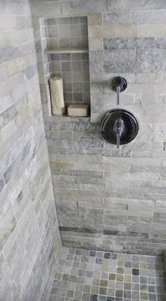 a bathroom with stone walls and tile flooring, including a shower head in the corner