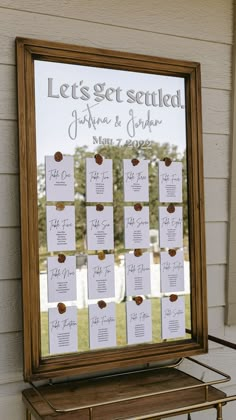 a wedding seating chart is displayed in front of a mirror on the side of a building