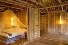 a bed with a mosquito net hanging from it's side in a bamboo room