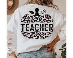 a woman wearing a white sweatshirt with the words teacher printed on it and an apple