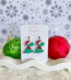 two christmas themed earrings are sitting on a shelf