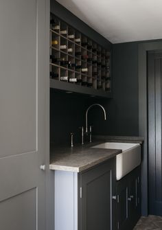 a kitchen with black walls and white counter tops, an open wine rack is on the far wall