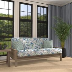 a couch sitting in front of two windows next to a table with a potted plant