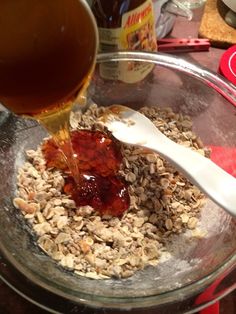 a bowl filled with oatmeal and jam being poured into the glass container