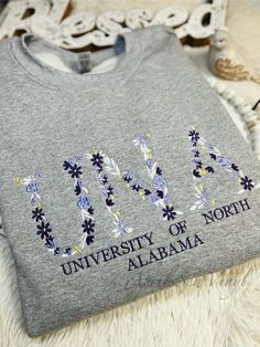 A custom embroidered sweatshirt with your college! This can be customized just how you want it, all of the floral letter and the wording below can be changed! Sweatshirts are a Unisex 50/50 Blend of cotton and polyester! Please leave the letters you want for floral, what colors you want the floral in and/or the phrase below Ex: UNA (university of Alabama) , White, Dark Purple, Light Purple and little bit of yellow Embroidery College Sweatshirt, Embroidered College Sweatshirt, College Embroidery, Custom Embroidered Sweatshirt, Purple Light, University Of Alabama, Gildan Sweatshirts