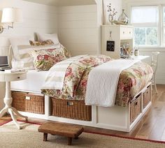 a bedroom with a bed, desk and storage baskets on the bottom shelf in front of it