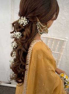 a woman with long hair and flowers in her hair is sitting on a white chair