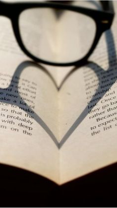 the shadow of a heart shaped book with glasses on it's face is shown in black and white