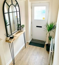 a hallway with a mirror, plant and potted plants