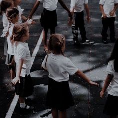 several children in school uniforms are walking down the street with their hands out to each other