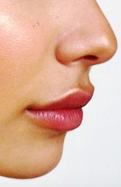 a close up of a woman's face with earrings on her ear and nose