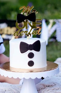 a white cake with black bow tie and mr onederate topper on it