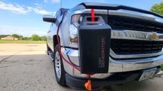 the front end of a silver truck with an orange cord attached to it