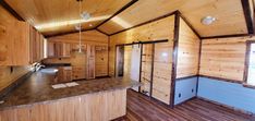 an empty kitchen with wooden walls and flooring