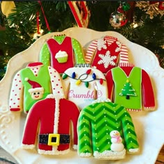 decorated christmas cookies on a plate in front of a tree