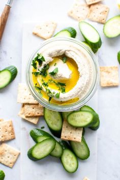 cucumbers and crackers are arranged around a small bowl with hummus on top