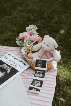 a teddy bear sitting on top of a blanket next to a basket filled with flowers