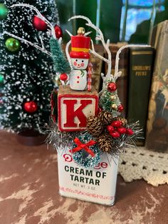 a small tin can with a snowman on top and christmas decorations around the bottom