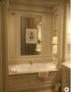 a white bath tub sitting under a bathroom mirror