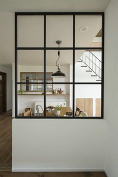 an open window shows the inside of a kitchen and dining room with stairs leading up to the second floor