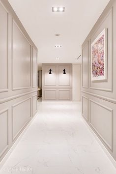 an empty hallway with white walls and flooring in the middle is lit by recessed lights