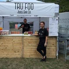 two people standing at a juice bar in front of a white tent with the words tru fooo on it