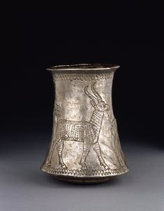 a silver vase with an animal design on it's side and a black background