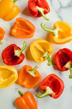 several peppers are arranged on a marble counter top, with one red and one yellow pepper in the middle