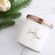 a white candle sitting next to a christmas tree