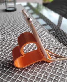 an orange pen holder sitting on top of a table next to a white ballpoint pen