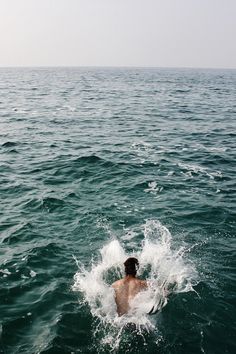 a man swimming in the ocean with his back to the camera