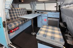 the interior of a camper van with blue walls and plaid upholstered seats