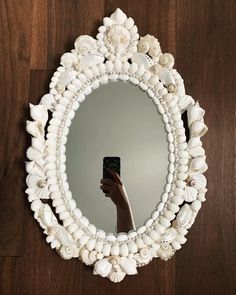 a person taking a selfie in front of a mirror with seashells on it