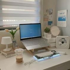 a laptop computer sitting on top of a white desk next to a cup of coffee