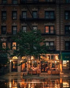 an image of a rainy night in the city with people sitting at tables and umbrellas