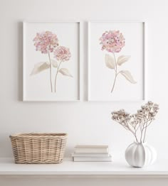 two framed flowers sit on a shelf next to a wicker basket and white vase