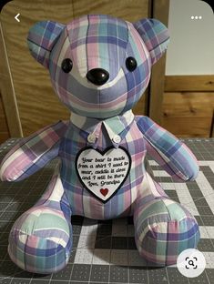 a blue and pink teddy bear sitting on top of a checkered tablecloth covered floor