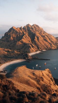 an aerial view of the ocean and mountains with boats in the water on it's shore