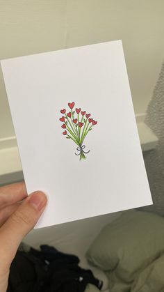 a person holding up a card with red flowers on it and hearts in the middle