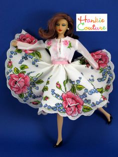 a doll is wearing a white dress with pink roses on it