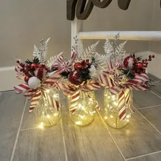 three mason jars with christmas lights and candy canes in them sitting on the floor