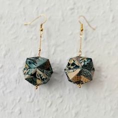 the earrings are decorated with green and yellow paper origami pieces, hanging from gold - plated earwires