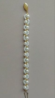 a gold and white beaded bracelet hanging on a wall