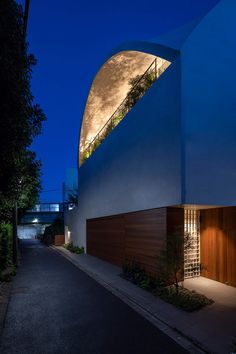 a building with an arched window and wooden doors on the side of it at night