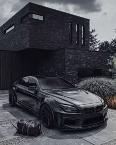 a black car is parked in front of a house with a bag on the ground