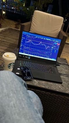 a laptop computer sitting on top of a wooden table next to a cup of coffee