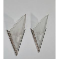 two clear glass objects on a white surface with silver lines around the edges and one is shaped like a triangle